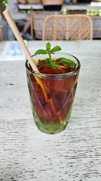 Refreshing Iced Black Tea with Mint Garnish in Textured Glass on Rustic Woo.. Stock Photos