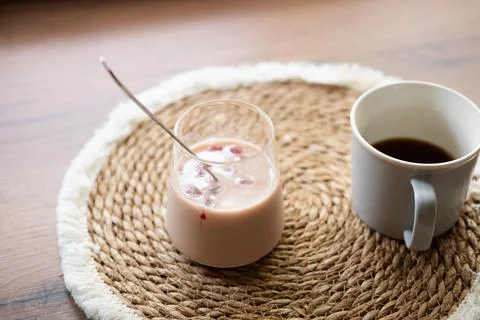 Refreshing iced coffee with cherry juice cubes served beside a cup of coffee Stock Photos