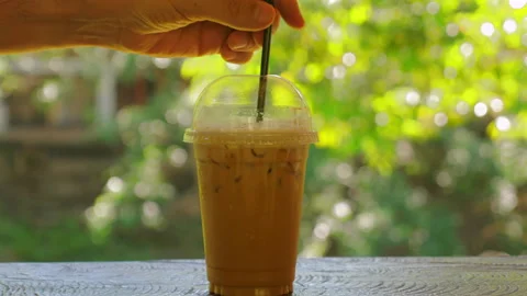 Refreshing iced coffee in clear plastic cup with black straw on wooden Stock Footage 284758042
