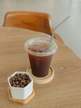 Refreshing iced coffee in a plastic cup with a straw, served with roasted b.. Stock Photos