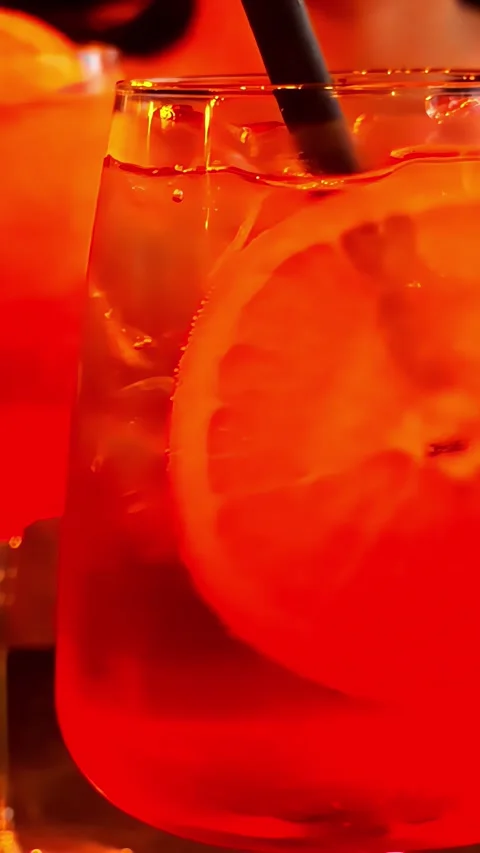 Refreshing iced drink with a slice of orange and straw in warm ambient light Stock Footage 339033338