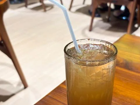 Refreshing Iced Lemon Tea Straw in a Ribbed Glass on a Wooden Table at a Cafe Stock Photos
