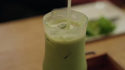 Refreshing iced matcha green tea latte in glass on wooden table. Stock Footage 337519883