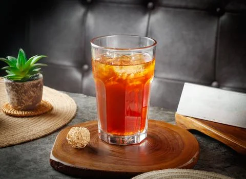 Refreshing iced tea beverage served on rustic wood coaster beside small suc.. Stock Photos