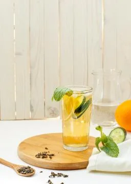 Refreshing iced tea with lemon and mint in a transparent glass on a light bac Stock Photos
