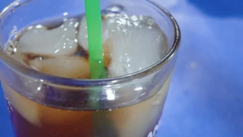 Refreshing iced tea served in a clear glass with a bright green straw. Video stock 343383976