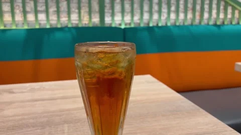 Refreshing Iced Tea in a Tall Glass on a Wooden Table with Bright Summer Stock Footage 330145205