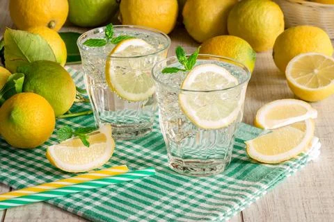 Refreshing lemon drinks served in clear glasses on a checkered cloth with fresh Stock Photos