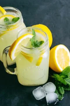 Refreshing lemonade drink with lemon slice and mint in jar on dark background Stock-Fotos