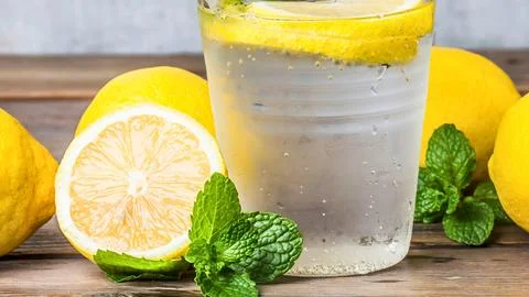 Refreshing lemonade with fresh mint and lemons on wooden surface Stock Photos