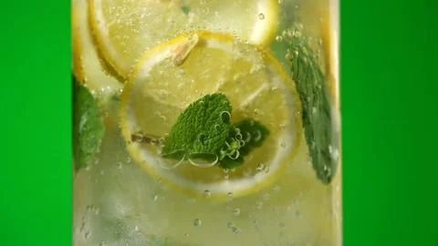 Refreshing lemonade with mint and ice in glass on green background Stock Photos