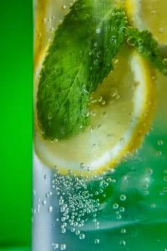 Refreshing lemonade with mint and ice in glass on green background Stock Photos