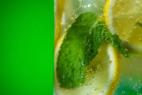 Refreshing lemonade with mint and ice in glass on green background Stock Photos