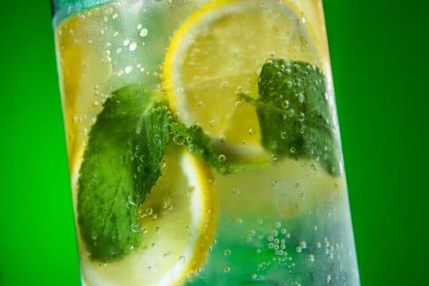 Refreshing lemonade with mint and ice in glass on green background Stock Photos
