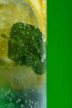 Refreshing lemonade with mint and ice in glass on green background Stock Photos