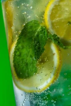 Refreshing lemonade with mint and ice in glass on green background Stock Photos