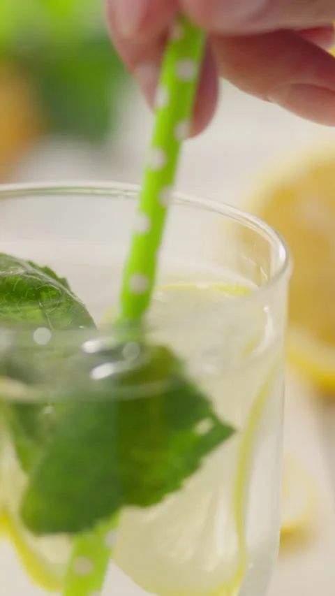 Refreshing lemonade preparation with mint and lemon slices in a clear glass Stock Footage 331724173