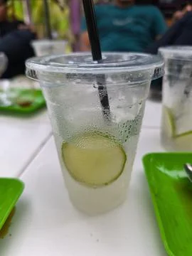 Refreshing Lime Drink in Plastic Cup with Condensation on White Table Stock Photos