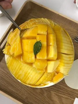 Refreshing mango bingsu with fluffy shaved ice, sweet mango chunks, and cre.. Stock Photos
