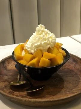 Refreshing mango bingsu with fluffy shaved ice, sweet mango chunks, and cre.. Stock Photos
