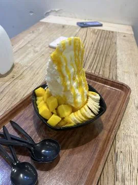 Refreshing mango bingsu with fluffy shaved ice, sweet mango chunks, and cre.. Stock Photos