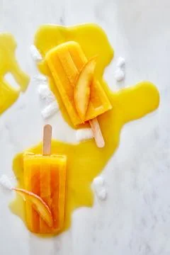 Refreshing mango ice cream with slice peach on a wooden stick on a marble Stock Photos