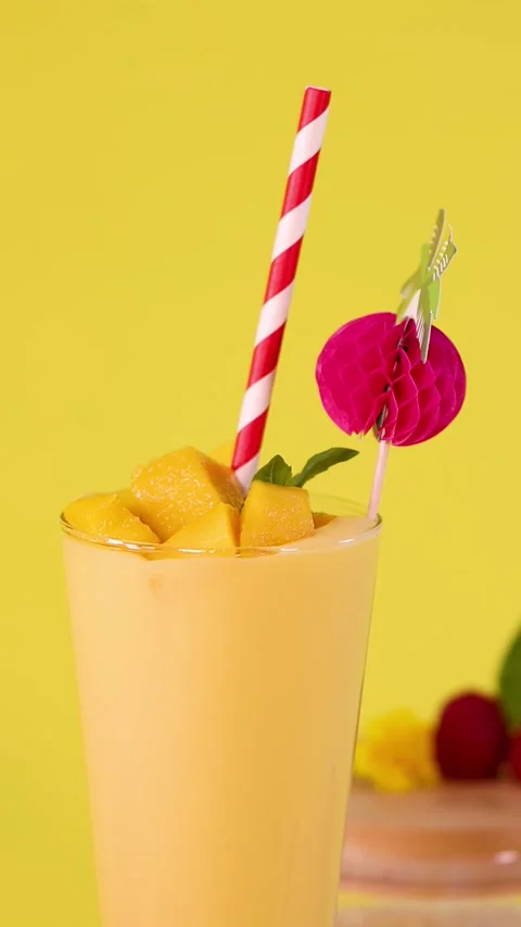 Refreshing Mango Smoothie Glass with Colorful Straw on Yellow Background Stock Footage 322557244