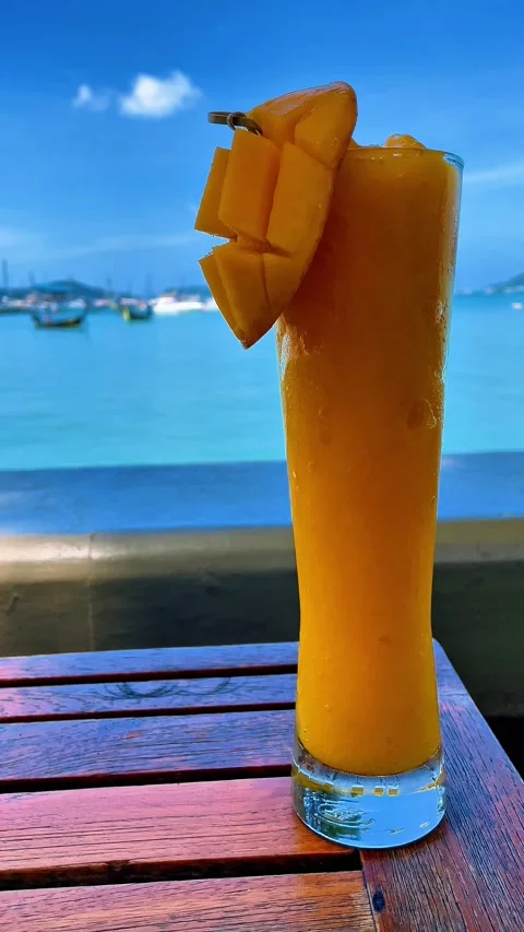 Refreshing mango smoothie with a peaceful sea atmosphere, perfect for a relaxing Vídeos de archivo 312423174
