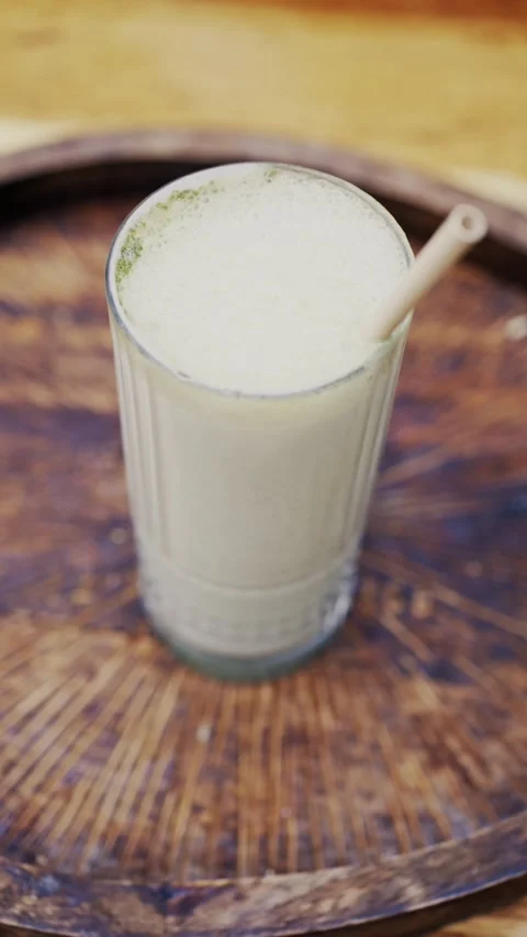 Refreshing matcha green tea latte in tall glass served on wooden tray in br.. Stock Footage 339373564