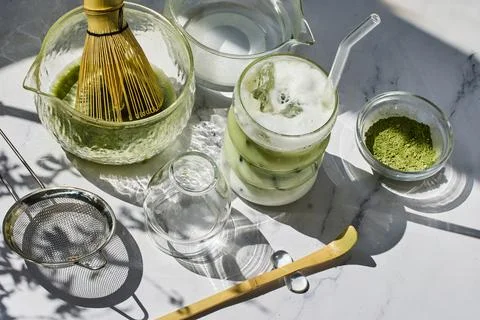 Refreshing Matcha Setup. A sunlit arrangement of matcha tea tools with a frothy Stock Photos