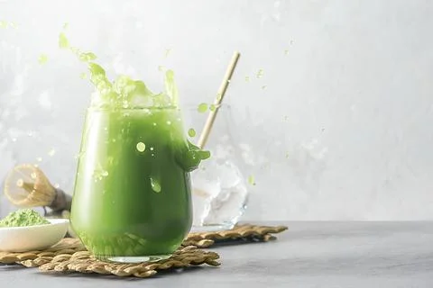Refreshing matcha tea with ice and splashes on a gray background with copy sp Foto stock
