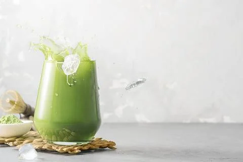 Refreshing matcha tea with ice and splashes on a gray background with copy sp Фото