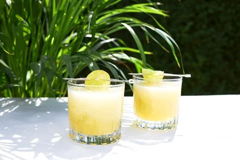 Refreshing melon smoothie with ice and lime in the sun. Summer cooling drinks. Stock Photos