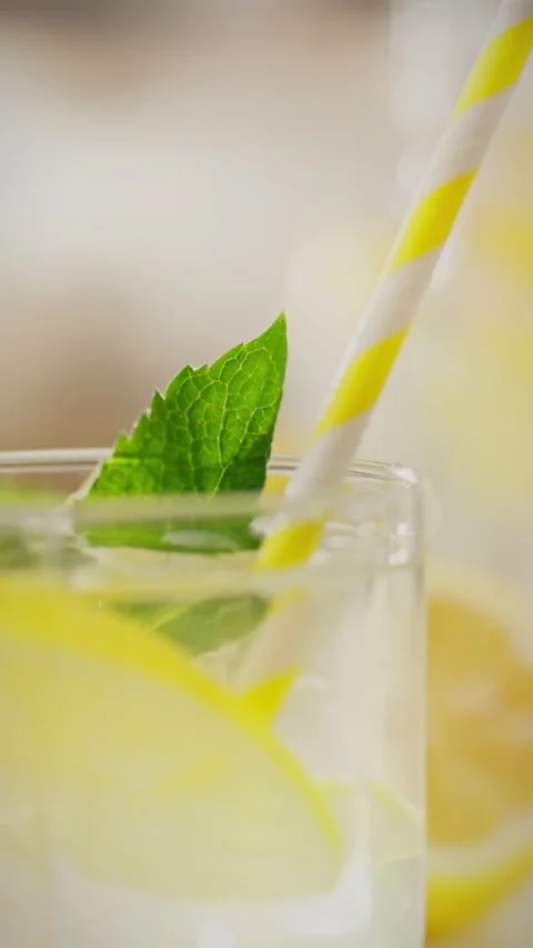 Refreshing mint and lemon drink served with a striped straw in a clear glass Stock Footage 331724126