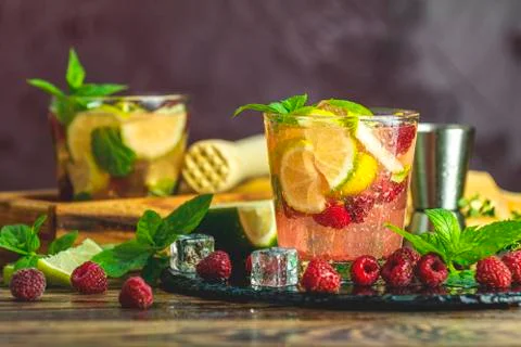 Refreshing mint cocktail mojito with rum, lime, mint, thyme, ice and raspberr Stock Photos