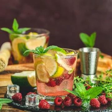 Refreshing mint cocktail mojito with rum, lime, mint, thyme, ice and raspberr Stock Photos