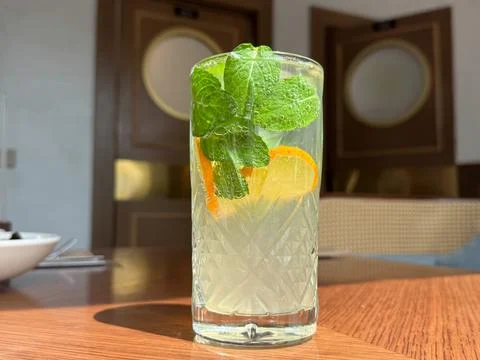 Refreshing mint lemonade cocktail with orange slices in a textured glass on Stock Photos