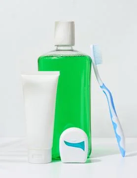 Refreshing mouthwash in a transparent plastic bottle and dental floss on a .. Stock Photos