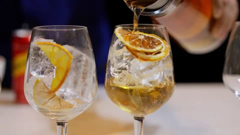 Refreshing orange cocktail being expertly poured from a jar into a glass filled Video stock 249886559