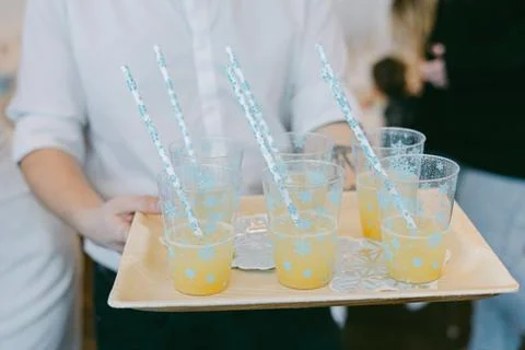 Refreshing orange drinks on a tray with festive straws at a joyous gathering in Stock Photos