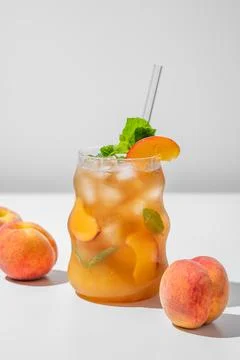 Refreshing peach iced lemonade with mint in a glass on a light background w.. Stock Photos