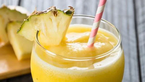Refreshing pineapple smoothie garnished with a pineapple wedge and straw Stock Photos