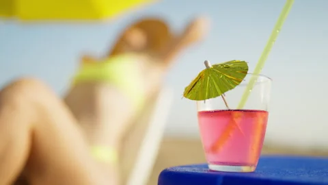 Refreshing pink cocktail with a straw and a small paper umbrella on a small.. Stock Footage 340902762