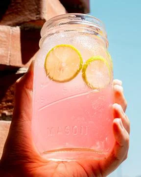 Refreshing pink lemonade held in one hand. Stock Photos