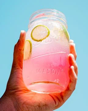 Refreshing pink lemonade held in one hand. Stock Photos