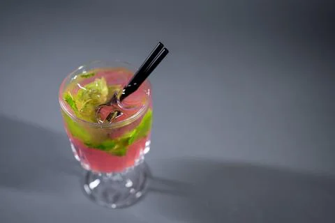 Refreshing pink lemonade with mint or rose cocktail in glass on grey background Stock Photos