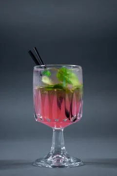Refreshing pink lemonade with mint or rose cocktail in glass on grey background Stock Photos