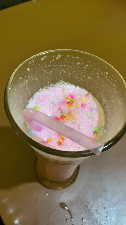 Refreshing pink strawberry milkshake with sprinkles in a glass close up Stock Footage 340141342
