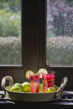 Refreshing raspberry and lime lemonade in pink glasses on the windowsill Stock Photos