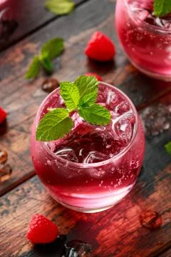 Refreshing raspberry cocktail with ice and mint on wooden table Stock Photos